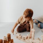 Young boy constructing with wooden building blocks, promoting creativity and play.