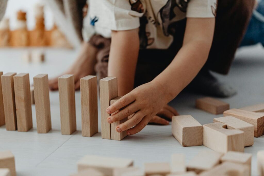 A close-up of a child arranging wooden blocks on the floor, focused on play.