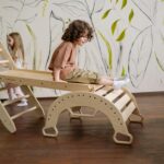 A child enjoying playtime on a wooden slide in a decorated indoor playroom.
