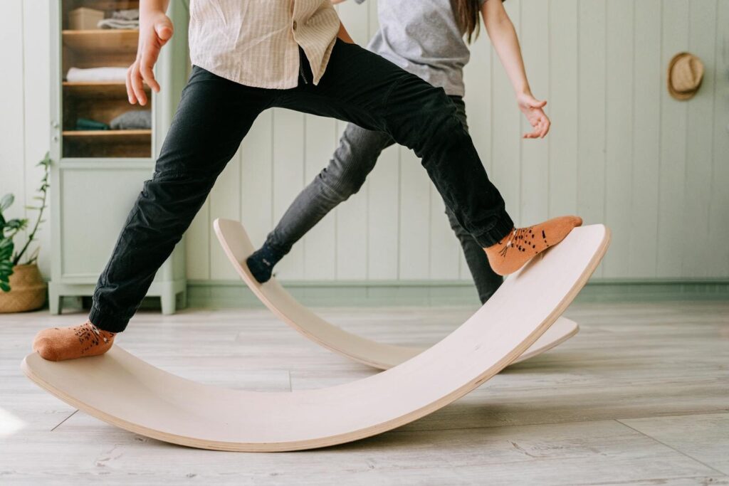 Two kids playing on wooden balance boards indoors, focusing on balance and mindful activities.