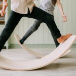 Two kids playing on wooden balance boards indoors, focusing on balance and mindful activities.